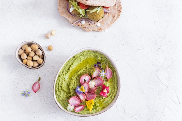 Photo bol d'houmous vert avec radis cuit au four et fleurs