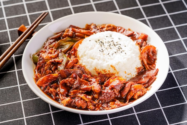 Un bol de kimchi avec du riz sur un tapis noir.