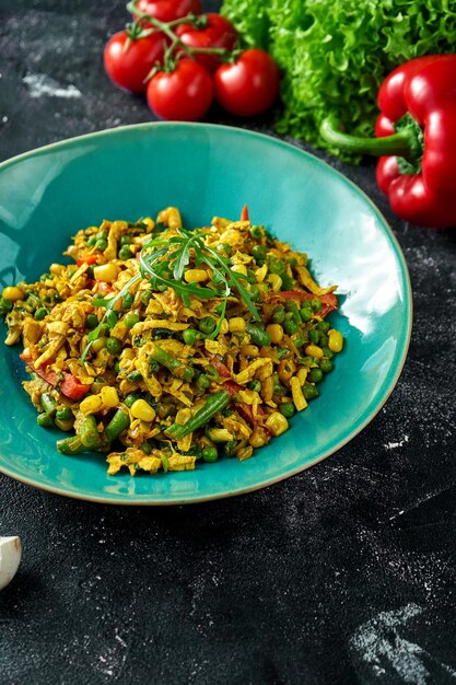 Bol avec légumes frits au wok et omelette sur fond noir