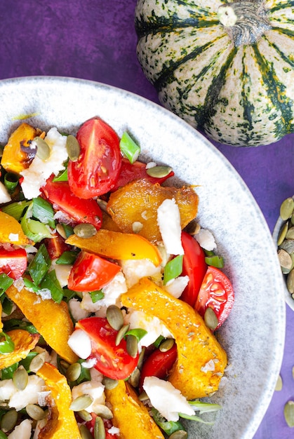 Un bol de légumes rôtis avec des citrouilles sur le côté.