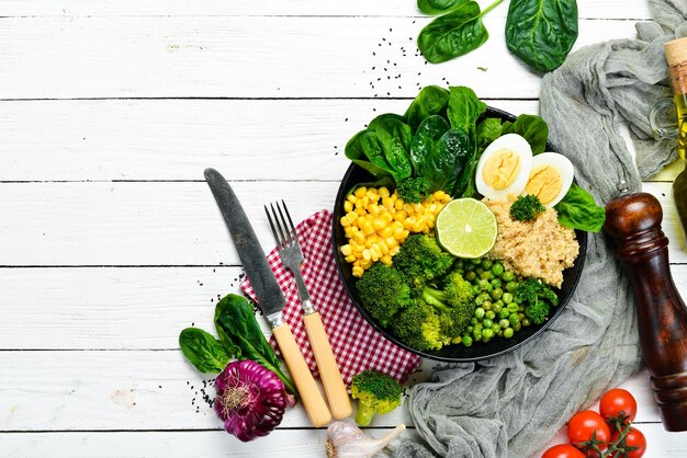 Bol de légumes verts Bouddha quinoa pois verts maïs épinards brocoli oeuf aliments sains Vue de dessus Espace libre pour votre texte