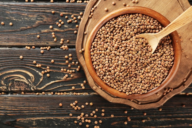 Bol avec lentilles brunes et cuillère sur fond de bois