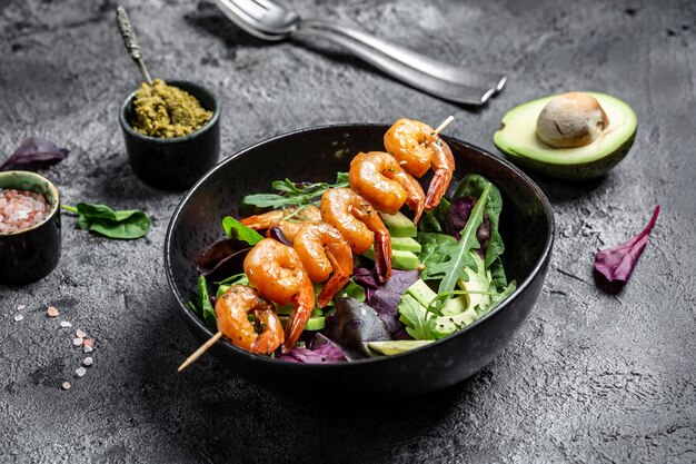 Bol à lunch végétarien à faible teneur en glucides avec avocat, salade fraîche, crevettes grillées et sauce pesto. Concept d'une alimentation saine. vue de dessus.