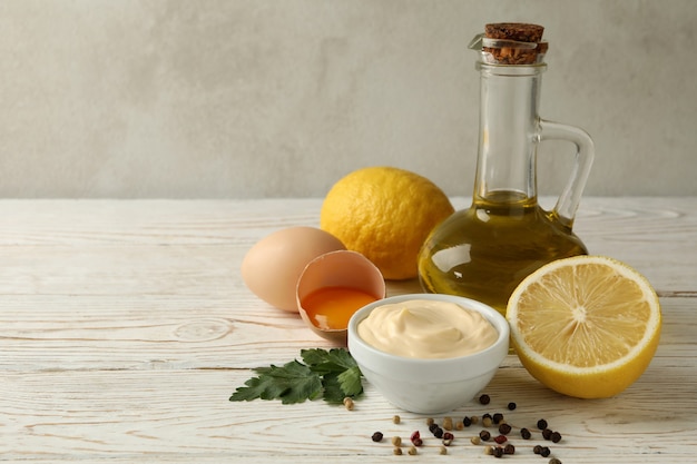 Bol avec de la mayonnaise et des ingrédients pour la cuisson sur fond de bois