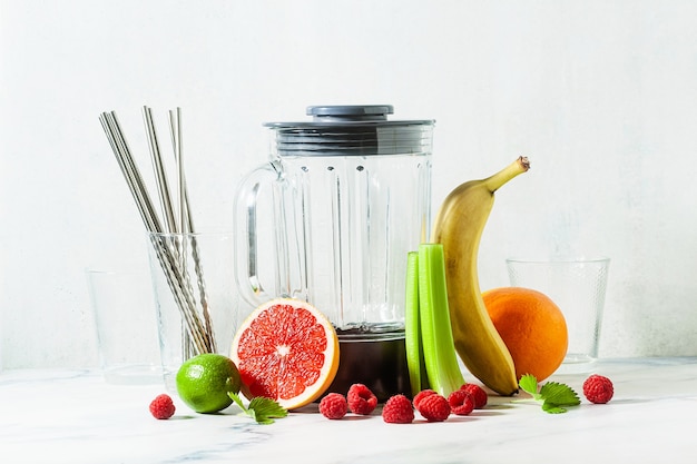 Bol mélangeur de smoothie en verre vide et ingrédients sur la table.