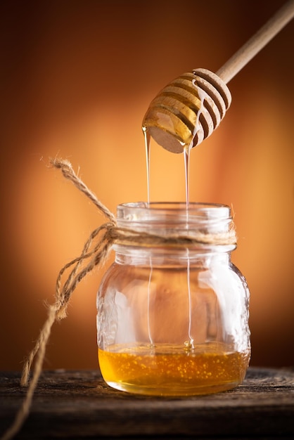 Pot De Miel Et Cuillère De Bois Sur La Table De La Lumière Orange