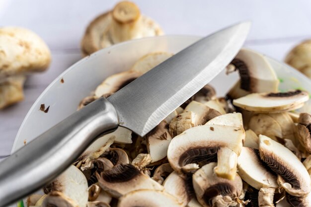 Un bol avec des morceaux de champignons frais couper les champignons avec un couteau