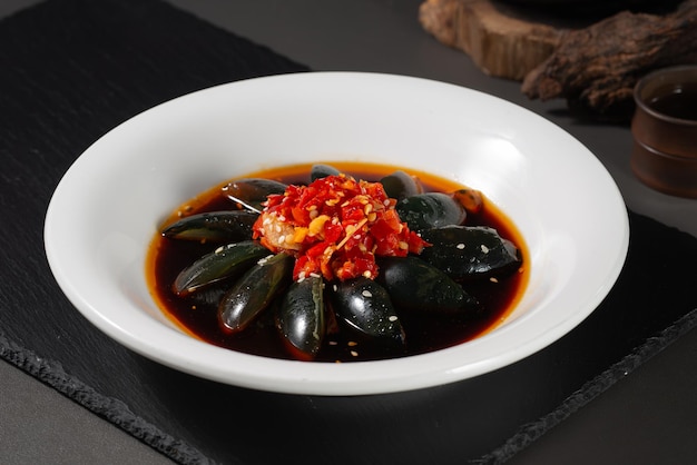 Un bol de moules avec une sauce rouge sur le dessus