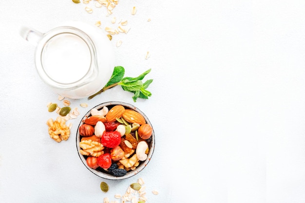 Bol de muesli et ingrédients pour un petit-déjeuner sain Noix de granola flocons de fruits secs et yaourt grec sur l'espace de copie de table blanche