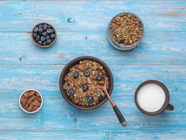 Un bol de muesli avec des noix et des ingrédients sur une table bleue. Mise à plat.