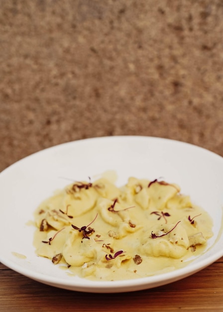 Un bol de nourriture blanc avec une sauce jaune et un fond marron.