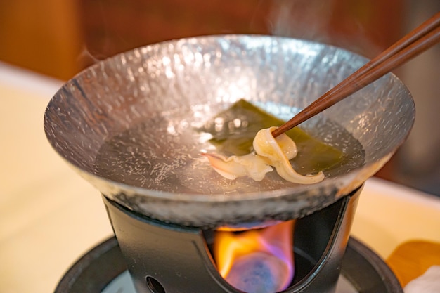 Un bol de nourriture sur un feu avec un bâton de nourriture dessus