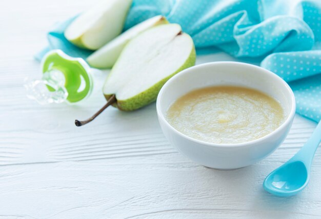 Bol avec de la nourriture pour bébé et poires sur table