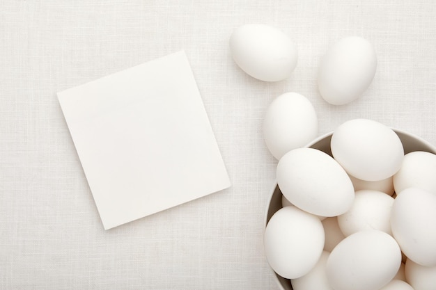 Bol d'oeufs blancs sur table avec carte de maquette