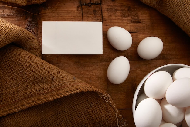 Bol d'oeufs blancs sur table rustique avec carte de maquette