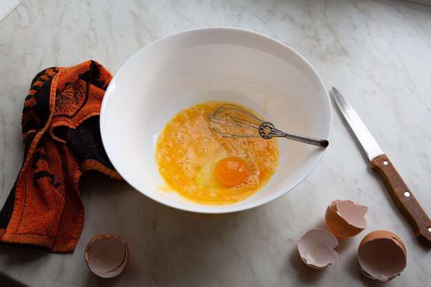 Bol d'oeufs crus sur la table de la cuisine par la fenêtre