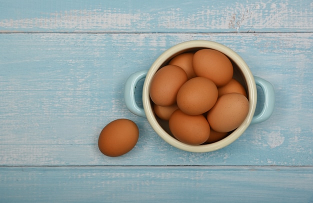 Bol d'oeufs de poule bruns sur table bleue