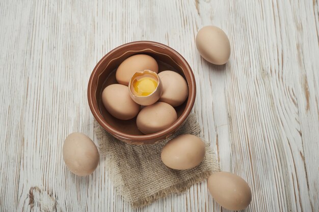 Bol d'oeufs de poule crus sur le fond en bois