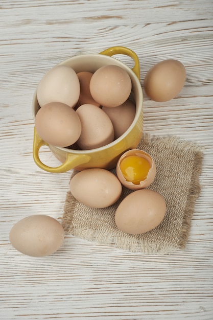 Bol d'oeufs de poule crus sur le fond en bois