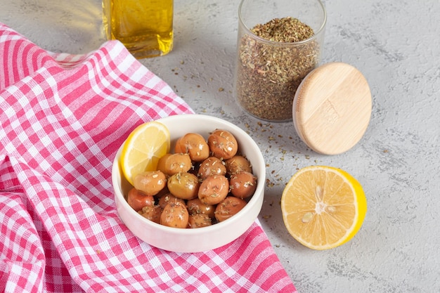 Un bol d'olives vertes au citron et à l'huile d'olive sur un sol en béton