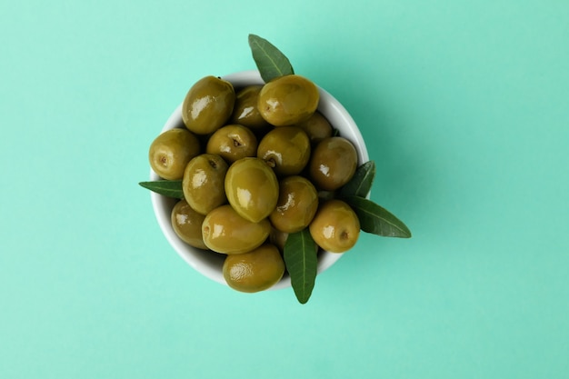 Bol d'olives vertes et de feuilles sur fond isolé de menthe