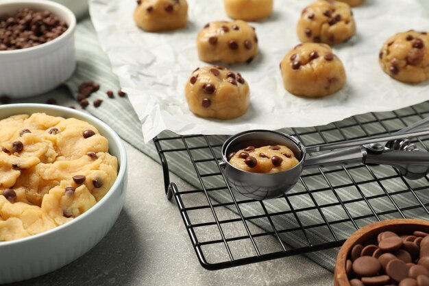 Un bol avec de la pâte et des biscuits au chocolat cru sur une table gris clair en gros plan