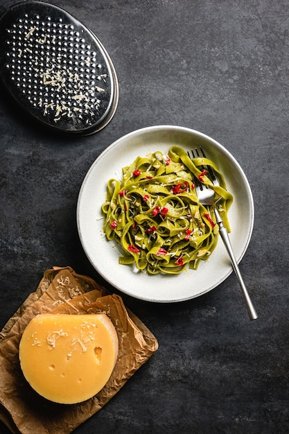 Un bol de pâtes aux épinards tagliatelles avec piment rouge, fromage vieilli râpé et huile d'olive.