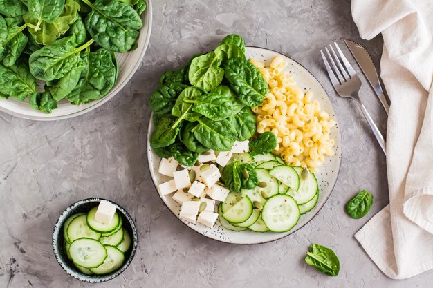 Bol avec pâtes, concombre, fromage et épinards sur la table Alimentation saine en vitamines Vue de dessus