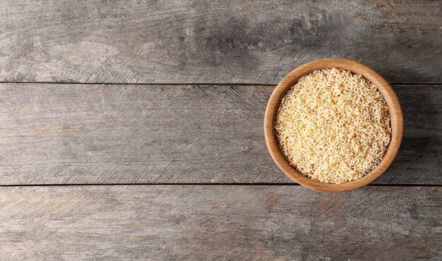 Bol avec des pâtes non cuites sur mur en bois