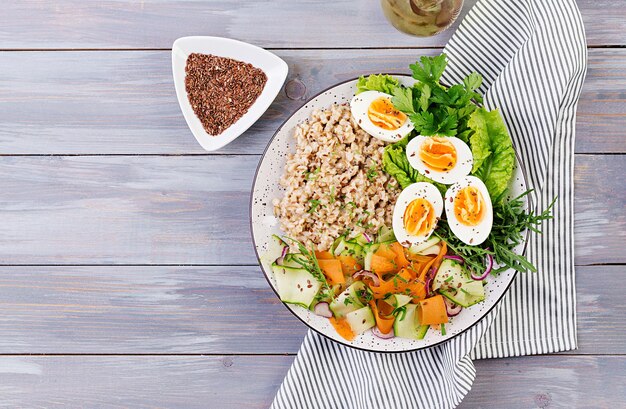 Un bol de petit déjeuner avec de la farine d'avoine, des courgettes, de la laitue, des carottes et des œufs bouillis Salade fraîche Nourriture saine Bol de bouddha végétarien Vue supérieure