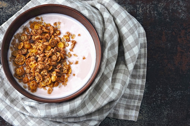 Bol de petit-déjeuner sain avec du yaourt frais et du granola.