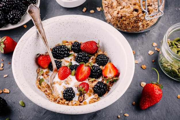 Bol de petit-déjeuner sain avec granola maison fraises mûres fraîches et graines de citrouille