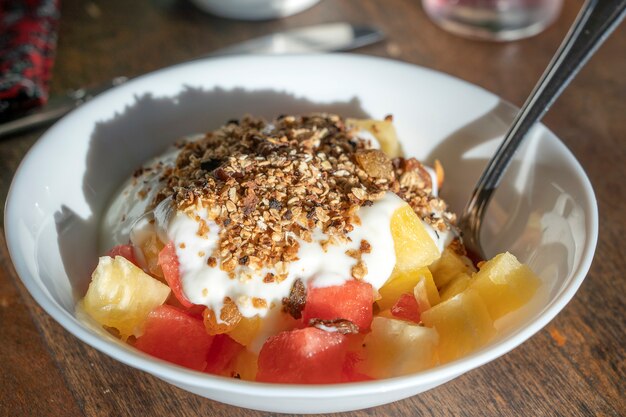 Bol de petit-déjeuner végétarien sain avec yogourt, céréales muesli, pastèque et ananas