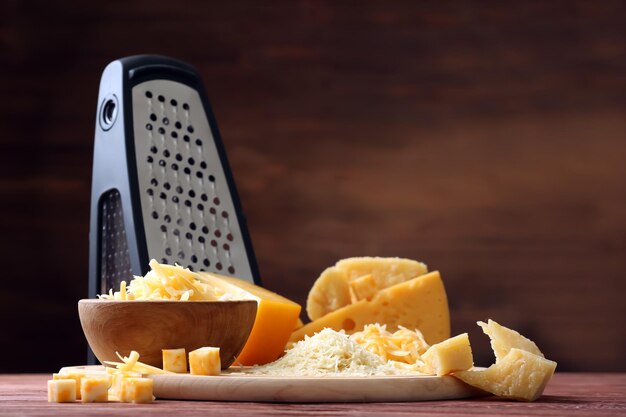 Photo bol de planche à découper avec fromage et râpe sur fond de bois