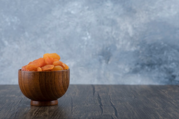 Un bol plein d'abricots secs sains sur une table en bois.