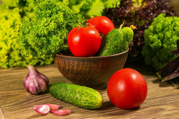 Un bol plein de bulbes d'ail Tomates et concombres sur une table en bois Salade verte en arrière-plan