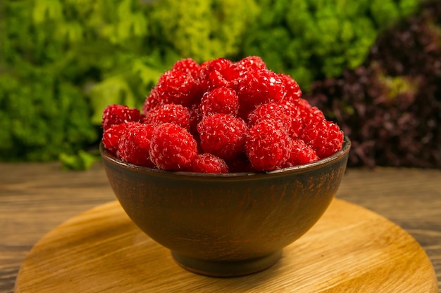 Bol plein de framboises mûres sur une table en bois