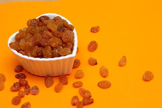 Bol plein de raisins secs sur fond coloré