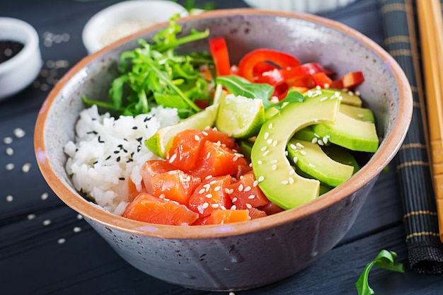 Bol de poisson haché au saumon hawaïen avec riz, avocat, paprika, graines de sésame et citron vert.