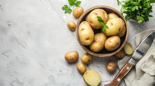 Un bol avec des pommes de terre crues et un couteau sur un fond clair