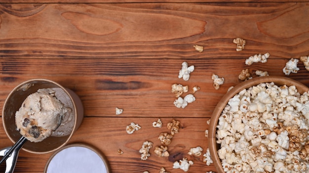 Bol de pop-corn et de crème glacée sur fond de bois.