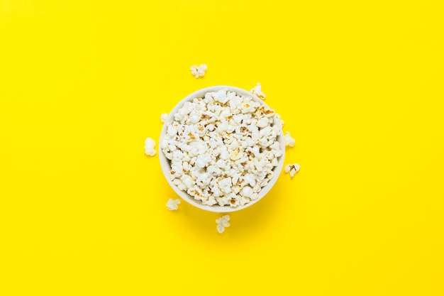 Bol avec pop-corn sur fond jaune. Mise à plat, vue de dessus.