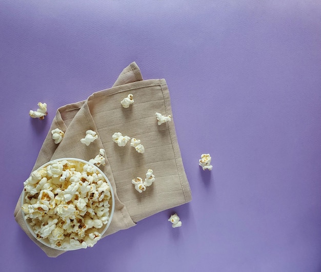 Bol de pop-corn salé sur un torchon beige sur fond coloré