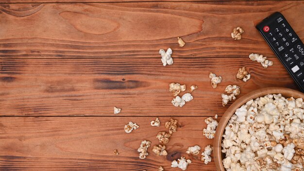 Bol de pop-corn et télécommande sur fond de bois.