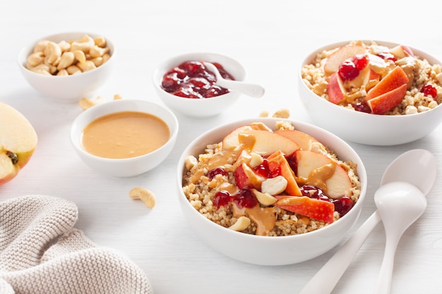 Bol de quinoa au beurre d'arachide et aux pommes avec confiture et noix de cajou pour un petit-déjeuner sain