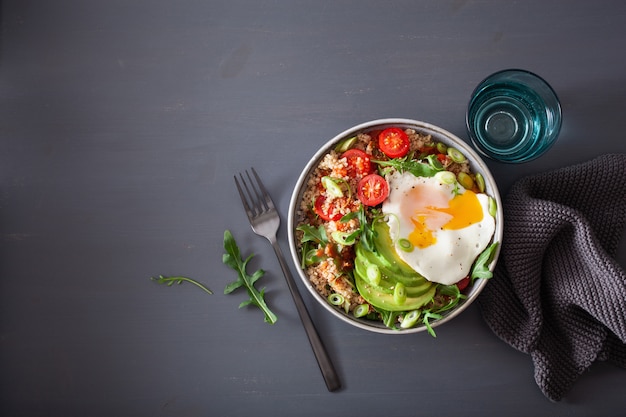 Bol de quinoa avec œuf au plat, avocat, tomate, roquette. Déjeuner végétarien sain