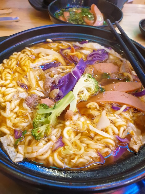 Photo un bol de ramen avec une feuille verte sur le dessus.