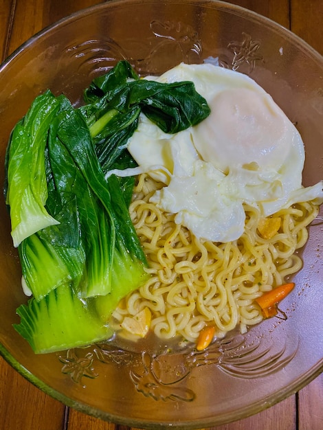 Un bol de ramen avec un légume vert sur le dessus