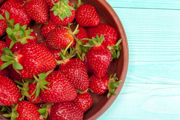 Bol de récolte de fraises sur table en bois close up