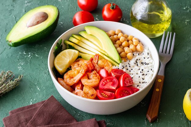 Un bol de riz, de crevettes, d'avocat, de tomates, de pois chiches et de citron vert Une alimentation saine